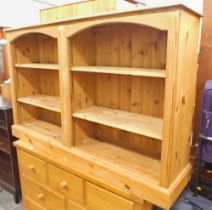 A pine two sectional bookcase, with plank top, over arched supports, on block base, 91cm high, 145cm