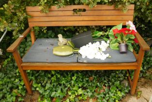 A wooden bench, cushions and artificial flowers.