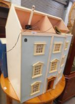 A three storey dolls house, painted in blue with lined and fitted interior and furniture.