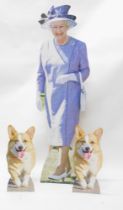 Large cardboard cut outs of Queen Elizabeth II and her two corgis.