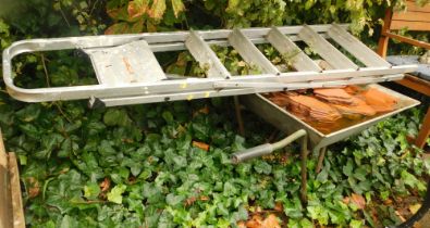 A metal wheelbarrow, various terracotta tiles, and an aluminium step ladder.