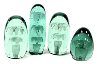 Four 19thC green glass dump paperweights, decorated internally with flowers, comprising one with thr