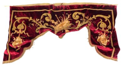 An early 20thC red velvet and gold brocade theatrical pelmet, embroidered with symbols of the arts,