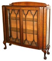 An early 20thC mahogany bow front display cabinet, with two astragal glazed doors enclosing two glas