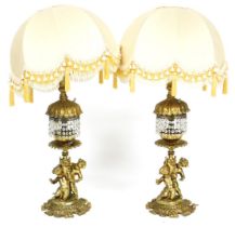 A pair of 20thC Continental brass table lamps, modelled with putti, on a scrolling leaf base, with b