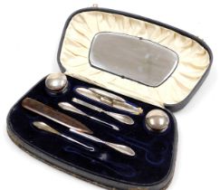 A George V silver backed part manicure set, boxed, comprising pair of silver lidded cut glass ointme