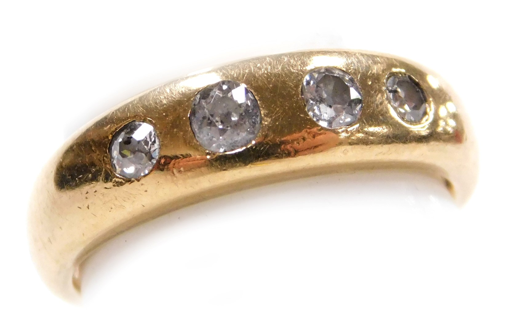 A diamond four stone gypsy ring, set with four rose cut diamonds in a yellow metal band stamped 18ct
