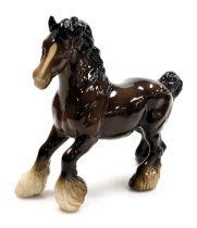 A pottery figure of a brown glazed gloss cantering shire horse.