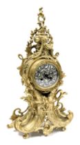 A late 19thC French rococo style brass cased mantel clock, the circular enamel dial with silver over