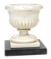 An early 19thC marble baptismal font, of semi fluted form, raised on a square plinth and black marbl