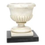 An early 19thC marble baptismal font, of semi fluted form, raised on a square plinth and black marbl