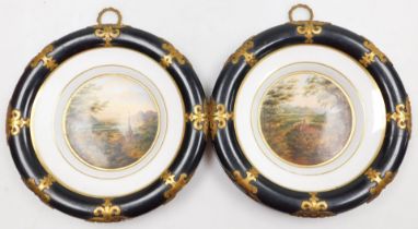 A pair of 19thC Continental porcelain plates, the central reserves painted with a river and castle l