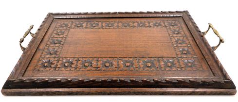 An early 20thC Arts and Crafts style oak twin handled tray, carved with flower heads, 53cm wide.