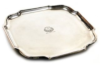 A George V silver piecrust salver, scallop shell crest engraved, raised on four ball feet, London 19