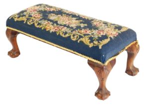 A Georgian style mahogany double stool, upholstered in rose pattern wool work tapestry, raised on fo