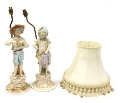 A pair of late 19thC Continental figural table lamps, modelled as boy and girl urchins with pomegran