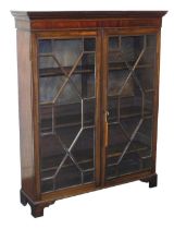 A George III style mahogany bookcase, the outswept pediment over a pair of astragal glazed doors, en