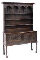 A Victorian oak dresser, the outswept pediment over a three shelf plate rack, with carved frieze and