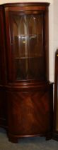 A corner display cabinet, with astragal glazed door over single panelled door, raised on brackets.