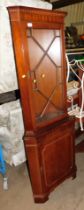 A mahogany veneered corner display cabinet, with astragal glazed door over a panel door.