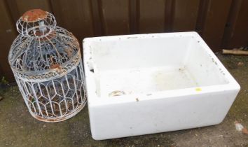 A white ceramic butler's sink and two bird cages.