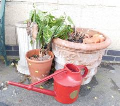 A stone garden plinth, a large stoneware planter, and a watering can.