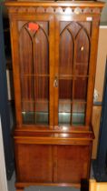 A reproduction yew wood bookcase, with two glazed doors to top, two panelled doors below, raised on