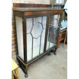 A display cabinet, of twin glazed sectional doors, raised on short cabriole support, terminating in