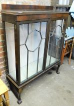 A display cabinet, of twin glazed sectional doors, raised on short cabriole support, terminating in