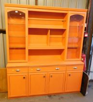 An orange painted dresser, with two glazed doors flanking shelving unit above single long drawer fla