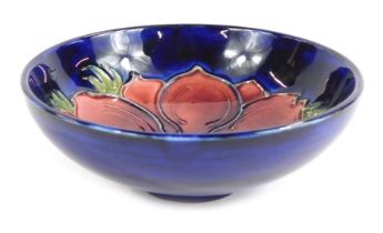 A Moorcroft pottery dish, decorated centrally with a flower against a blue ground, impressed marks t