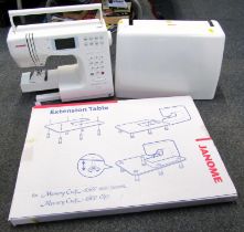 A Janome cased sewing machine, together with an extension table, boxed.