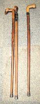 Three wooden walking sticks, each carved to handle with a skull.
