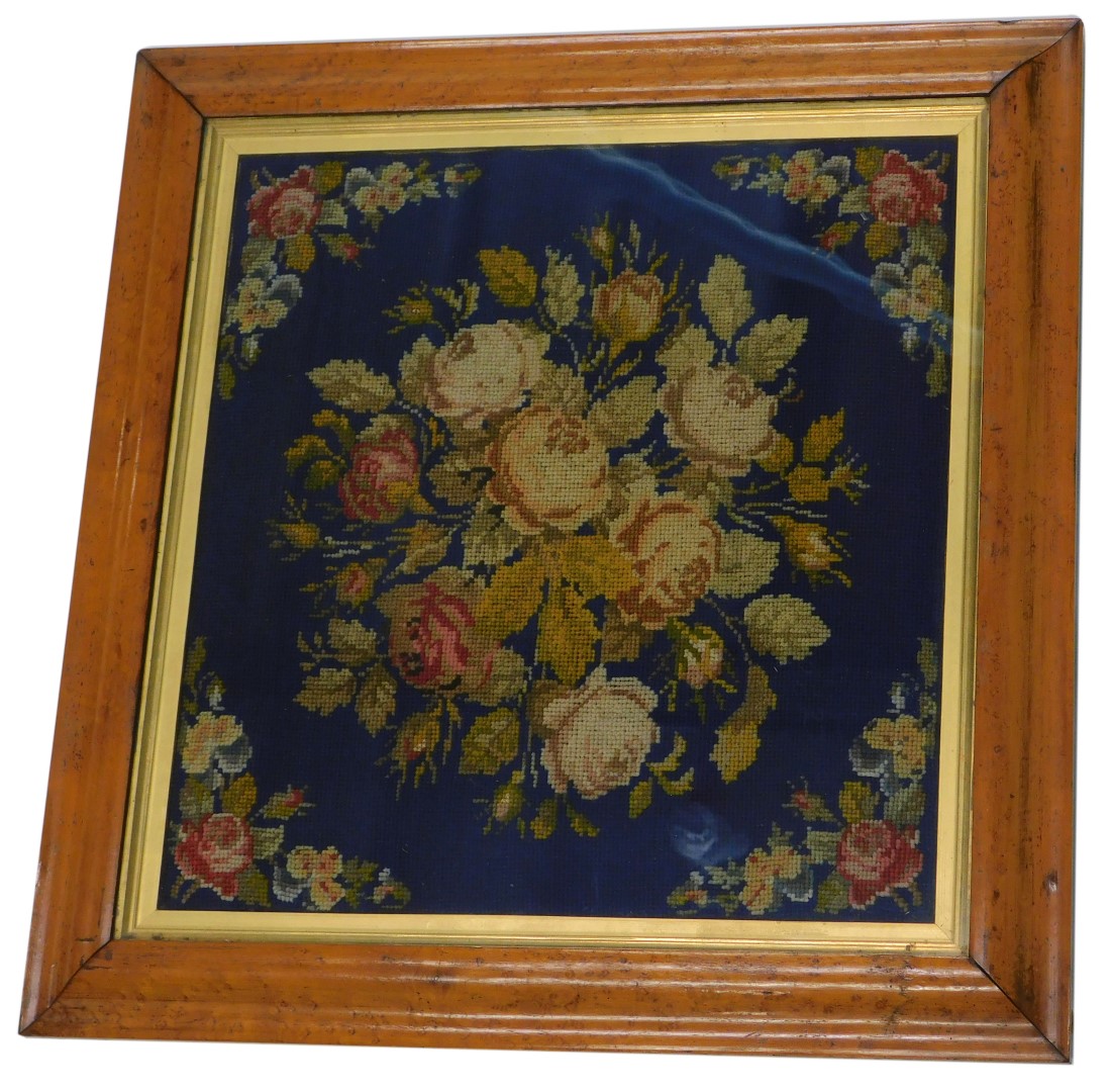 A Victorian wool work, embroidered with flowers on a blue ground within maple frame, 36cm x 35cm.