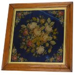 A Victorian wool work, embroidered with flowers on a blue ground within maple frame, 36cm x 35cm.