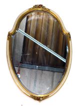 A gilt gesso and cream painted cartouche shaped wall mirror, with floral crest, 65cm high, 41cm wide