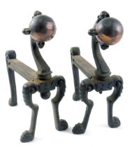 A pair of early 20thC black painted cast iron and copper fire dogs, each modelled with a ball and cl