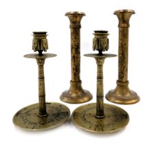 A pair of Egyptian revival brass candlesticks, decorated overall with masks, hieroglyphics etc., 12c