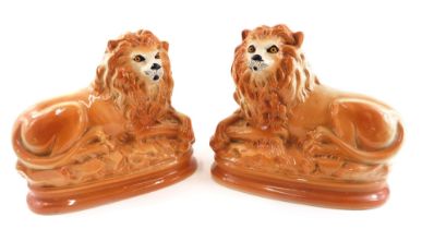 A pair of late Staffordshire pottery recumbent lions, each picked out in gilt, 29cm wide.