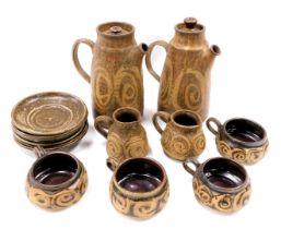 A studio pottery coffee set, on a brown ground with swirl glazed decoration to include two coffee po