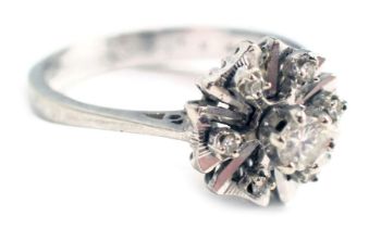 A diamond cluster ring, the petalated flower set with tiny diamonds and a central round brilliant cu