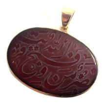 An Iranian agate pendant, of oval design with Arabic writing, in a rub over yellow metal border, 3.5