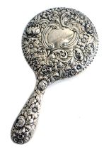 A silver mounted hand mirror, with bevelled plate, stamped sterling, decorated overall with flowers,