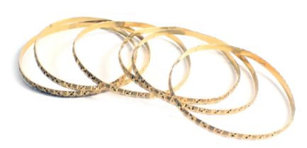 Six hammered yellow metal bangles, each with rubbed markings, 49.2g all in.