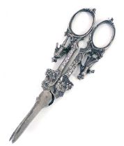 A pair of white metal grape scissors, with berry and vine detail and male and female figures to hand