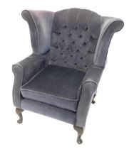 A wingback chair, upholstered in blue fabric on cabriole legs. The upholstery in this lot does not