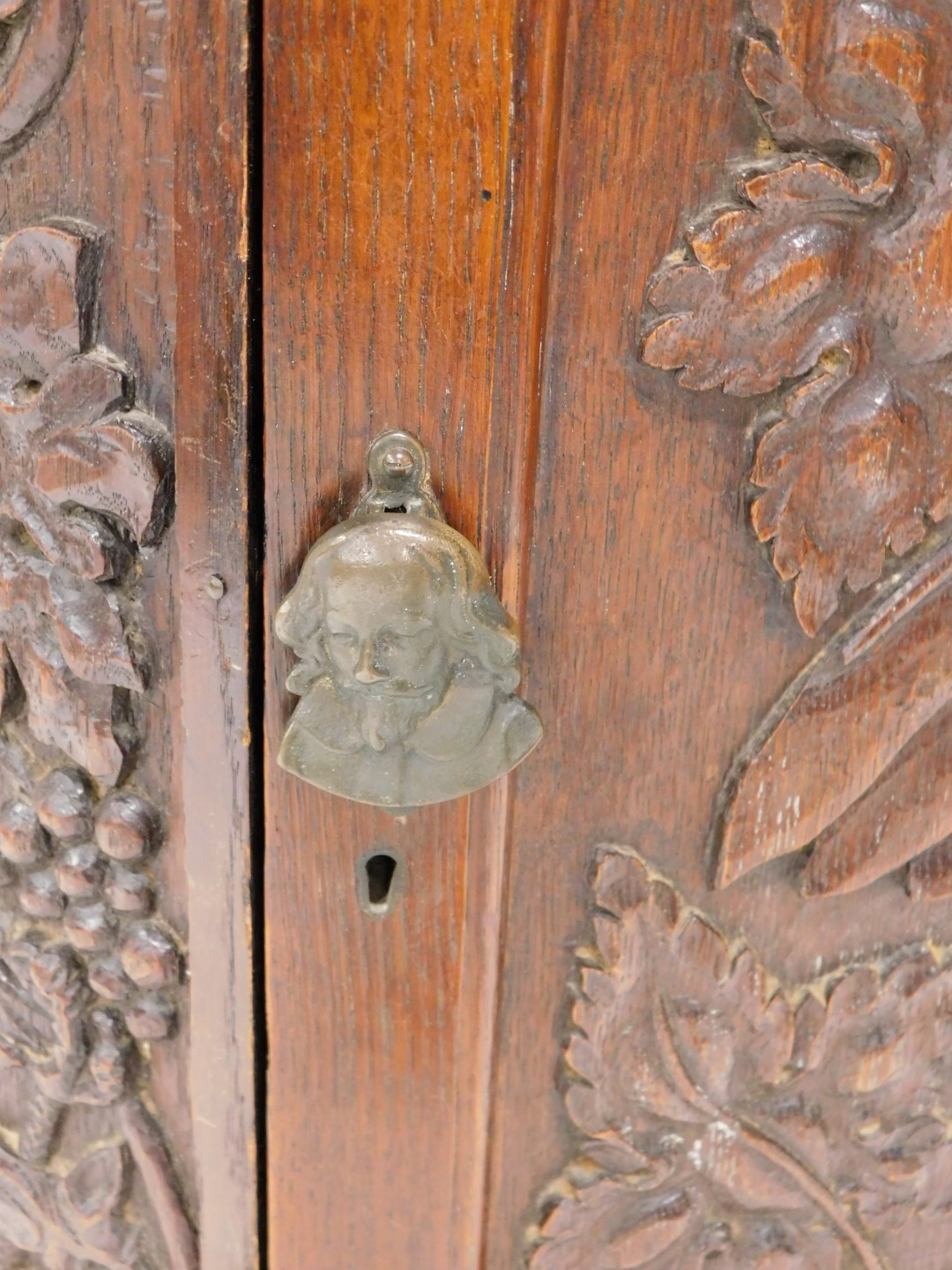 A carved oak side cabinet, with canted corners, the door decorated with grapes, leaves, etc., 89cm h - Image 2 of 2