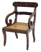 A Regency mahogany open armchair, the bar back carved with roundels and scrolls, with reeded shaped