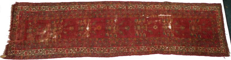 A Persian runner, with a design of flowers and geometric devices, on a red ground, (AF), 87cm wide,