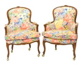 A set of four walnut French style armchairs, each upholstered in bright floral fabric on cabriole le